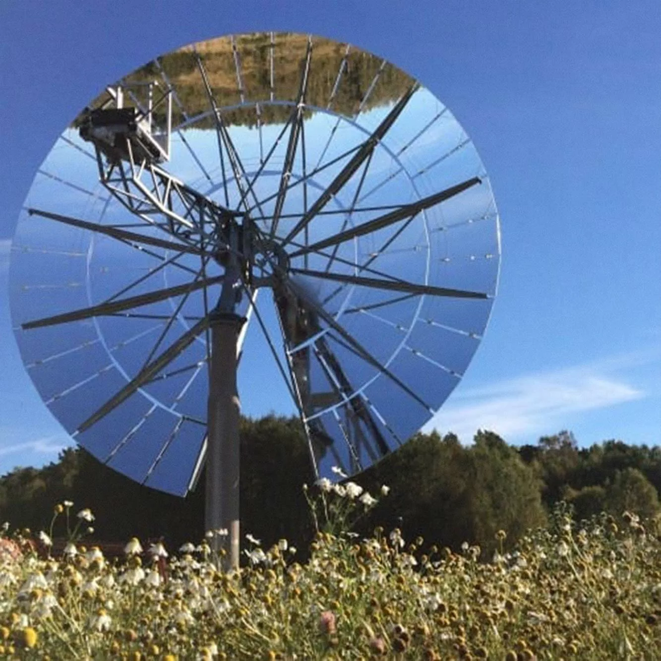 A solar concentrator with 66 mirror elements in front of a field on a sunny day