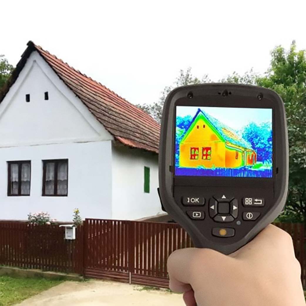 FLIR heat camera taking a picture of a house where heat leaks is visible